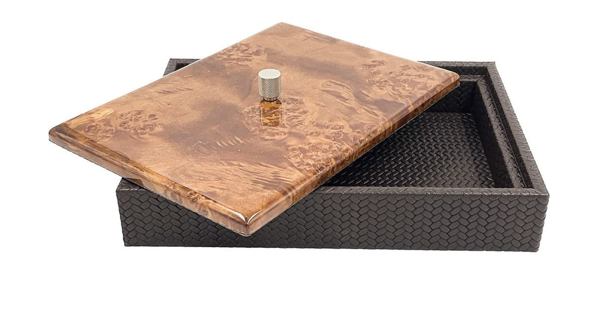 A leather storage box with a figured timber lid and a knurled steel knob, the lid set at an angle to show the leather interior.