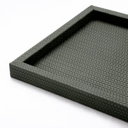 Raised corner of the 36 x 36 cm tray, the woven-embossed leather running the rim and turning down the outer face