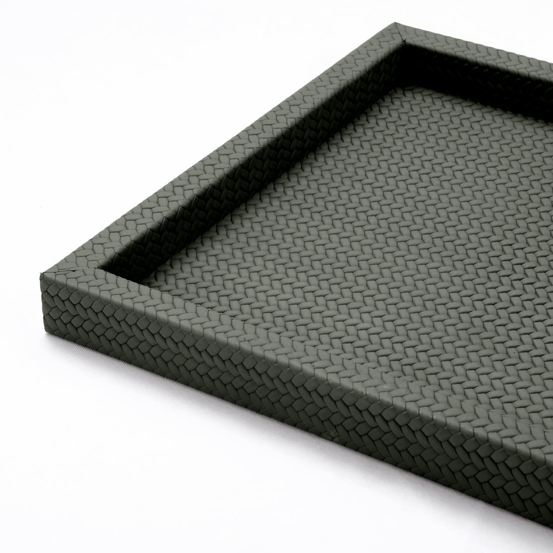 Raised corner of the 36 x 36 cm tray, the woven-embossed leather running the rim and turning down the outer face