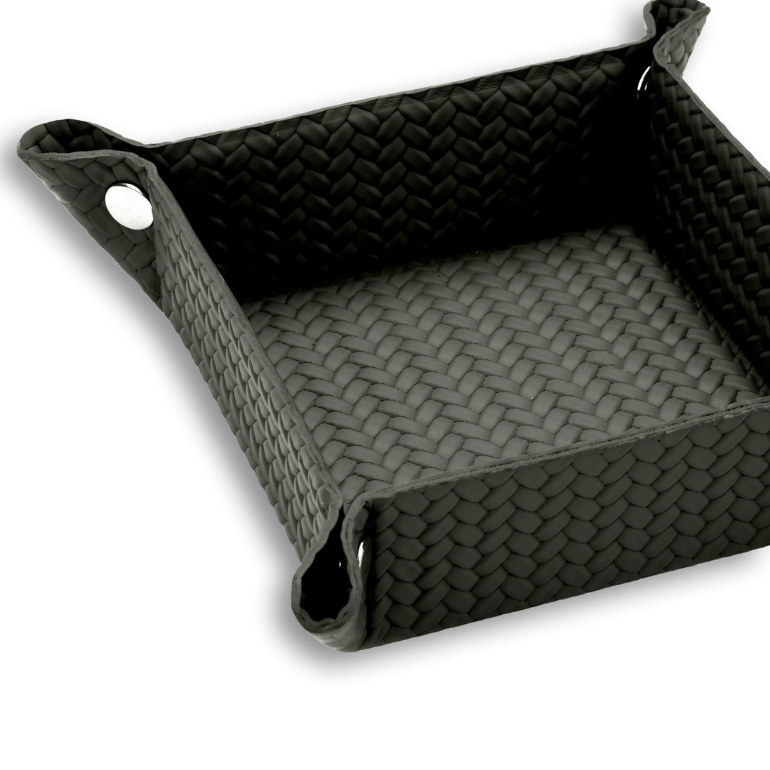 Corner of the 20 x 20 cm valet tray fastened with a polished metal press-stud, piping tracing the top edge of the woven leather