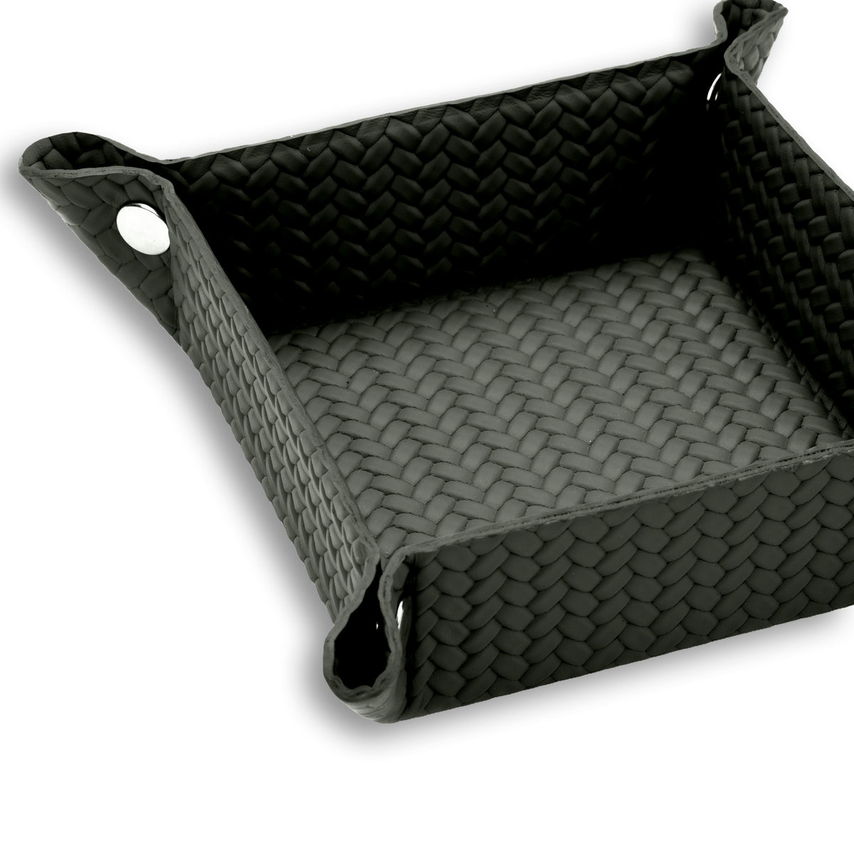 Corner of the 20 x 20 cm valet tray fastened with a polished metal press-stud, piping tracing the top edge of the woven leather
