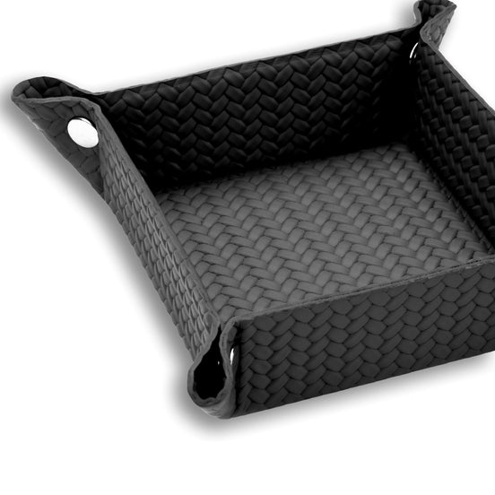 Black 15 × 15 cm valet tray close from above, a polished press stud drawing up the near corner
