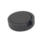 Round black leather coaster holder seen from above, a finger notch cut into the woven-embossed wall