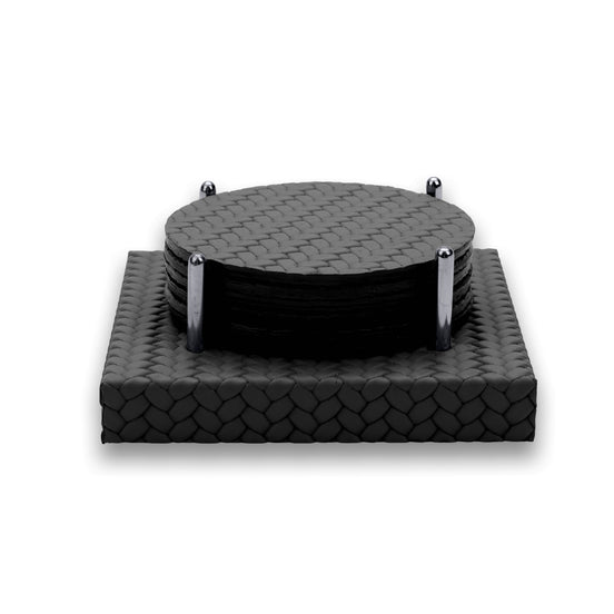 Six round black leather coasters stacked between four polished steel posts on a square woven-leather base