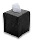 Black 11.5 × 11.5 cm tissue cover upright, a tissue drawn through the slot in its woven-embossed leather lid