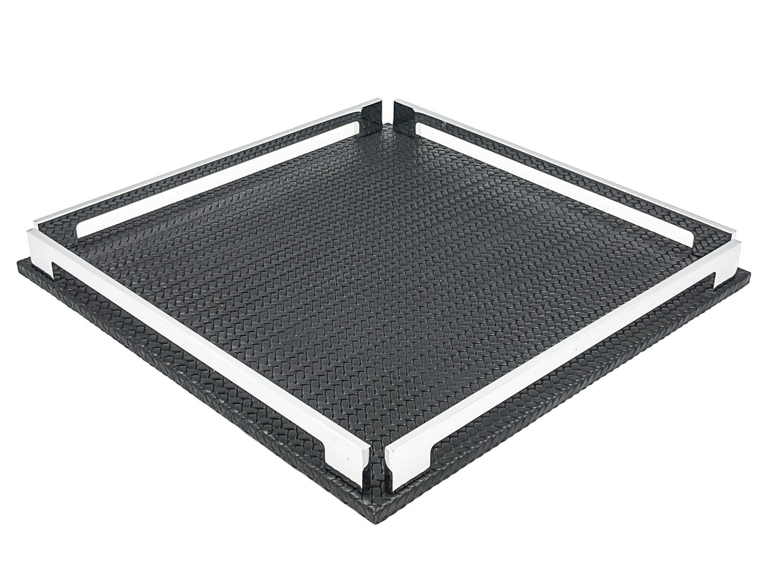 Black 37 × 37 cm square tray from above left, two full-length steel rails framing the woven-embossed leather floor