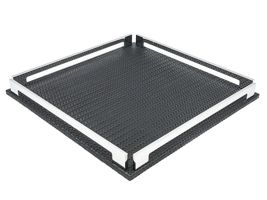 Black 37 × 37 cm square tray from above left, two full-length steel rails framing the woven-embossed leather floor