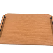 The 36.5 cm square panel seen low from the front, a coarse chevron plait embossed across the leather between two black metal carrying rails