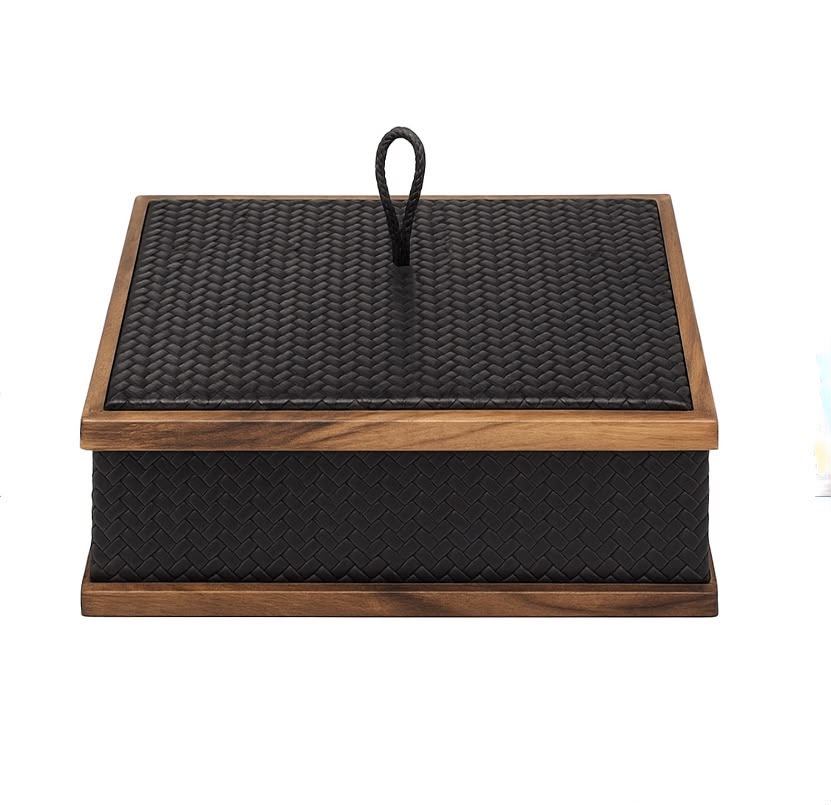 Black 26 × 26 cm box seen level, a plaited leather loop on the lid between walnut rails top and base