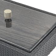 Close on a corner of the 27.5 x 20 cm box, the polished wood lid edge meeting scale-embossed leather beside a knurled metal knob