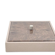The closed box seen level from the front, its mahogany lid seated flush inside the 27 x 27 cm woven leather rim
