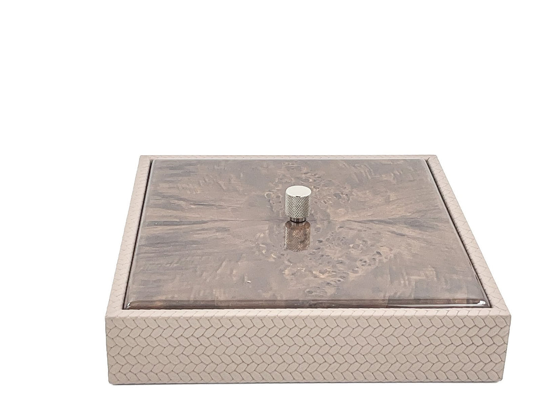 The closed box seen level from the front, its mahogany lid seated flush inside the 27 x 27 cm woven leather rim