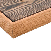 Close on the box corner, the lacquered mahogany lid edge above a mitred seam in the embossed leather