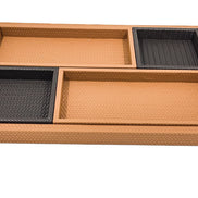 The set from above, the woven leather floor of the base tray still open along one side beyond the four inner trays