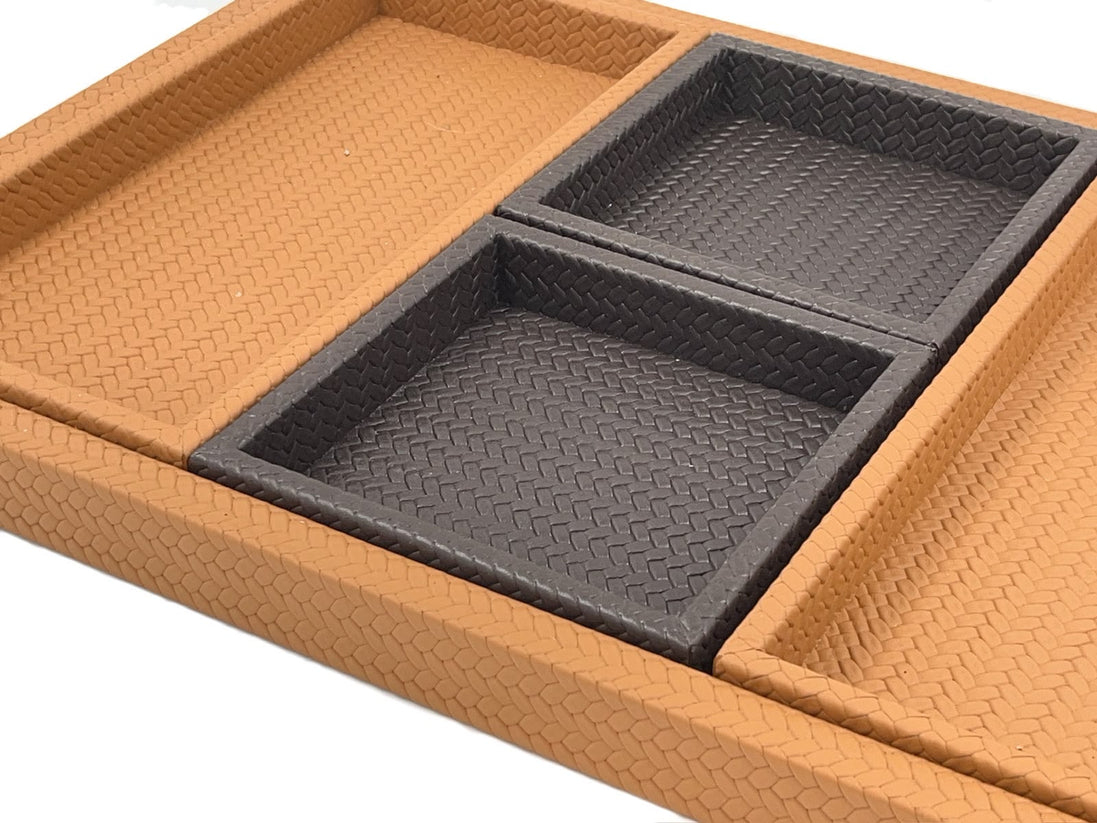 Close on two of the inner trays, their leather walls meeting square inside the deeper rim of the base