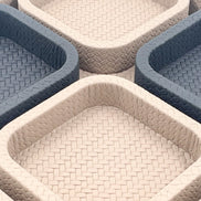 Close across the inner rims, a coarse plait on the darker trays against a finer weave on the pale leather ones