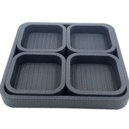 The charcoal set from above right, the base tray's woven leather visible between the four inset wells