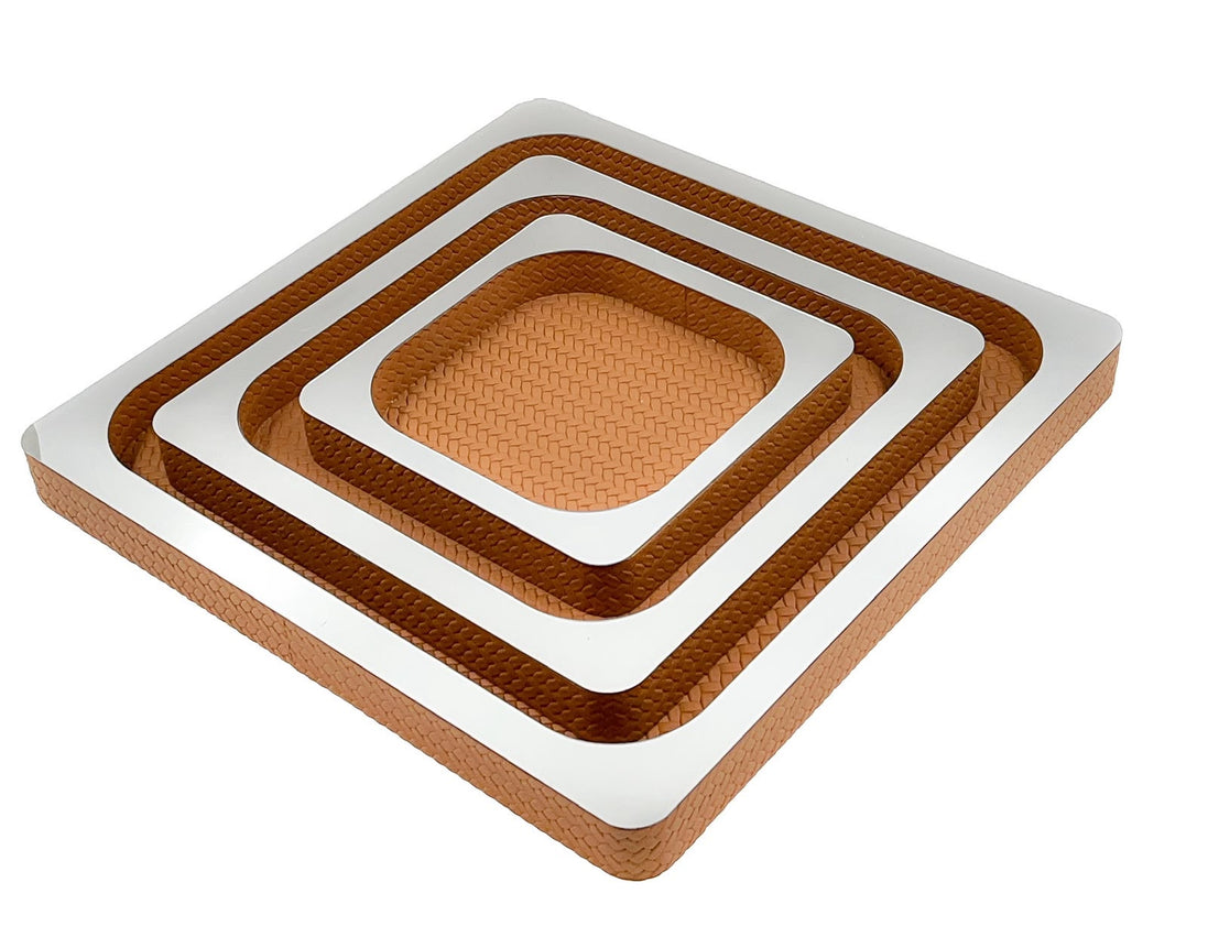 Three nested copper-toned leather squares, mirror-polished tops stepping down from the 41 cm outer tray to the 21 cm centre