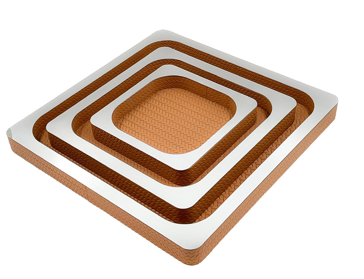 Three nested copper-toned leather squares, mirror-polished tops stepping down from the 41 cm outer tray to the 21 cm centre