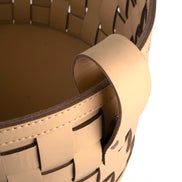 Close on a rolled leather handle, the strap end lapped and stitched over the basket's darker lining