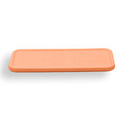 Warm orange placemat, the woven emboss picked out by the light across its 50 cm length