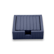 Navy 13 × 13 cm square leather coasters in their woven-embossed holder, finger notch cut at the front