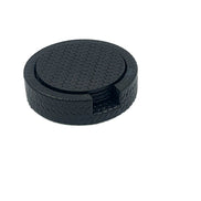 Navy Ø 10 cm leather coasters stacked in their round holder, woven-embossed faces and a notch cut in the rim