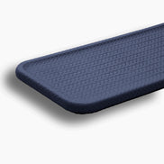 Close on a rounded corner of the navy slim tray, woven-embossed full-grain leather catching the light
