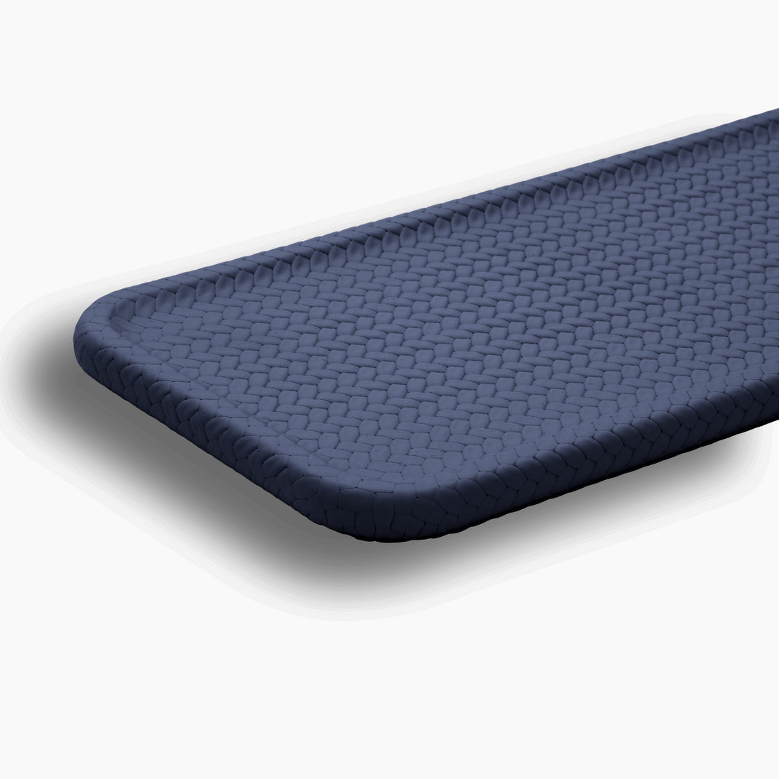 Close on a rounded corner of the navy slim tray, woven-embossed full-grain leather catching the light