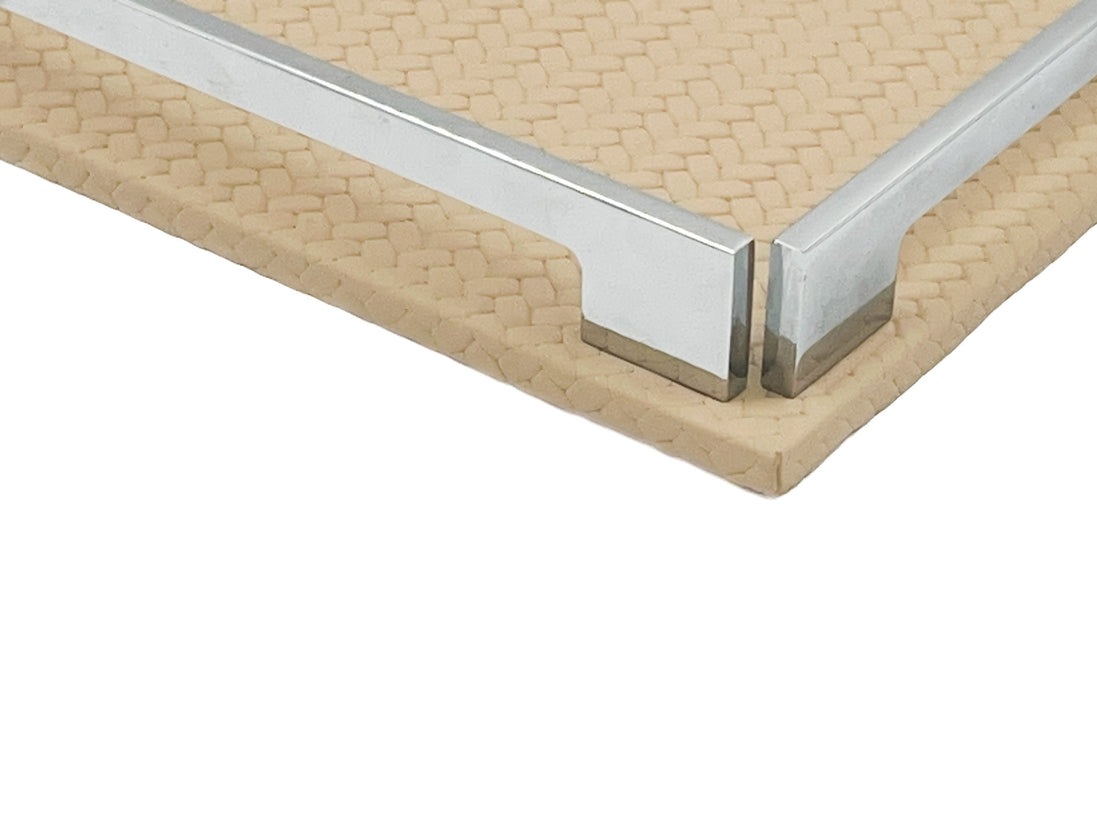 Close on a corner of the beige 30 cm tray, polished steel bracket seated on woven-embossed full-grain leather