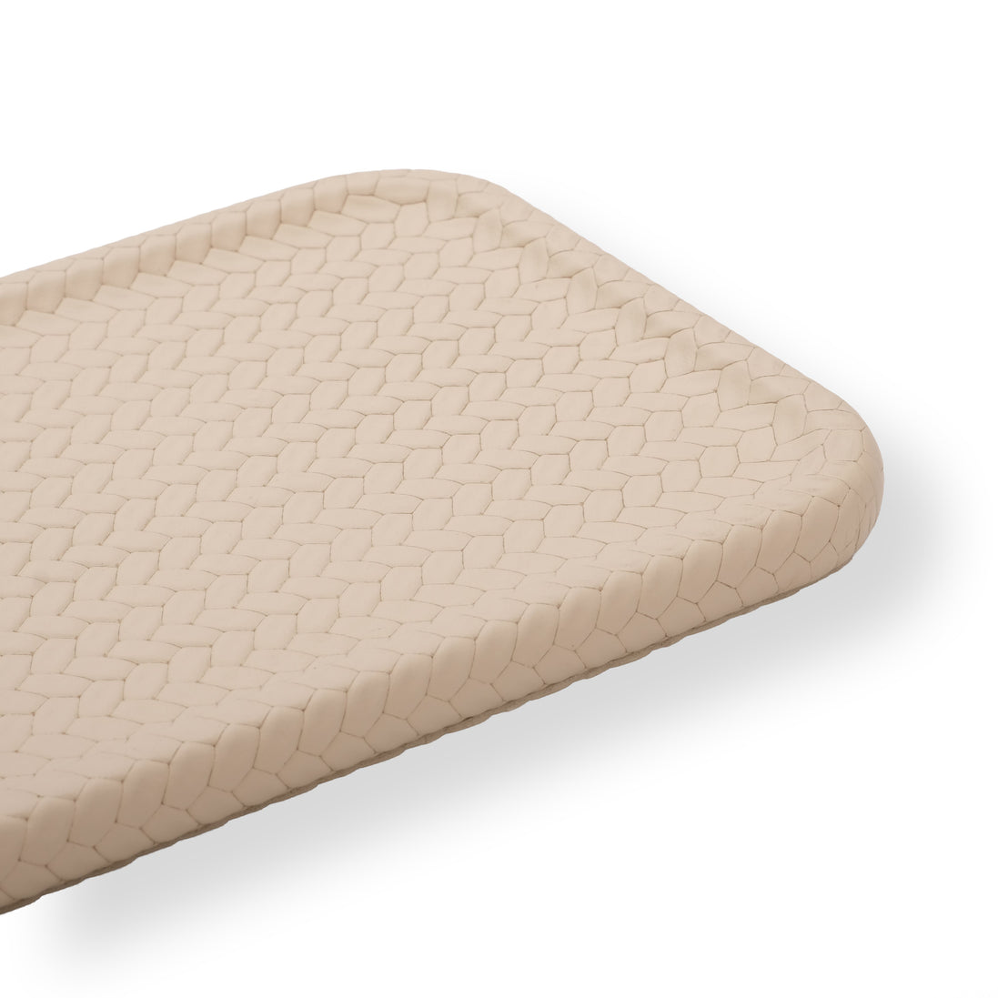 Close on the beige slim tray's rounded corner, pale woven-embossed leather across the 16.5 cm width