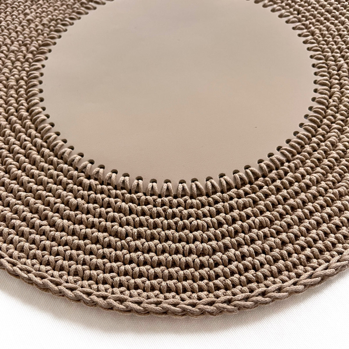 Close on the sand placemat, whipstitch teeth joining the leather centre to the crocheted cord rows