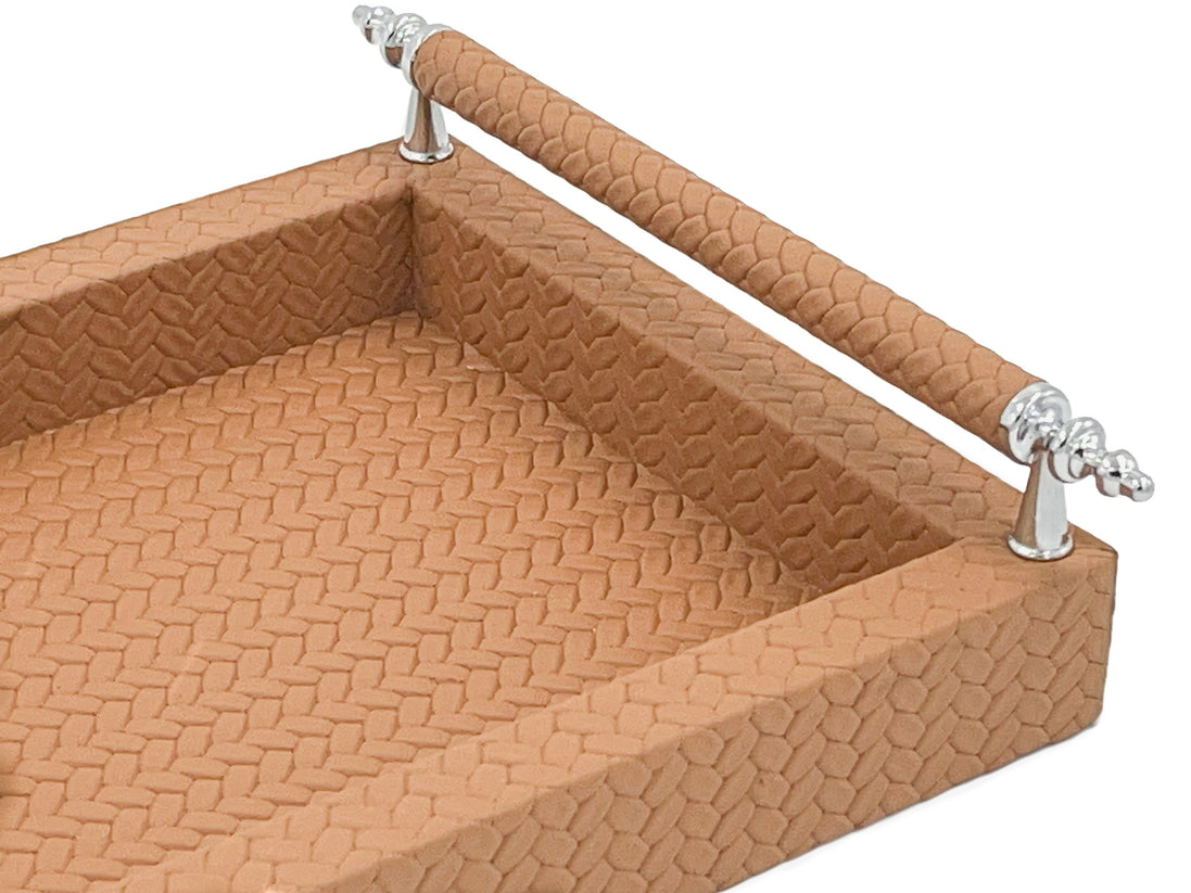 Close inside the tan tray, woven-embossed leather at full scale beneath a handle rail on its steel posts
