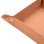 Close on a corner of the tan valet tray, press stud and woven-embossed full-grain leather at full scale