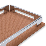 Close along the tan tray's long side, polished rail and side notch, woven-embossed leather receding