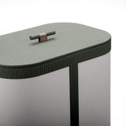 Closed olive leather lid on the 50 cm tall hamper, wooden toggle set into the woven surface