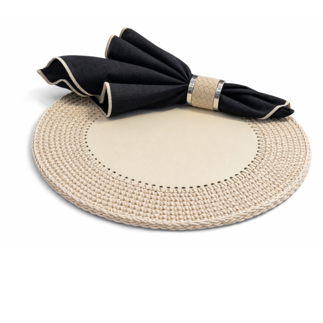 The cream placemat at an angle, black napkin folded above its crocheted 36 cm cord border