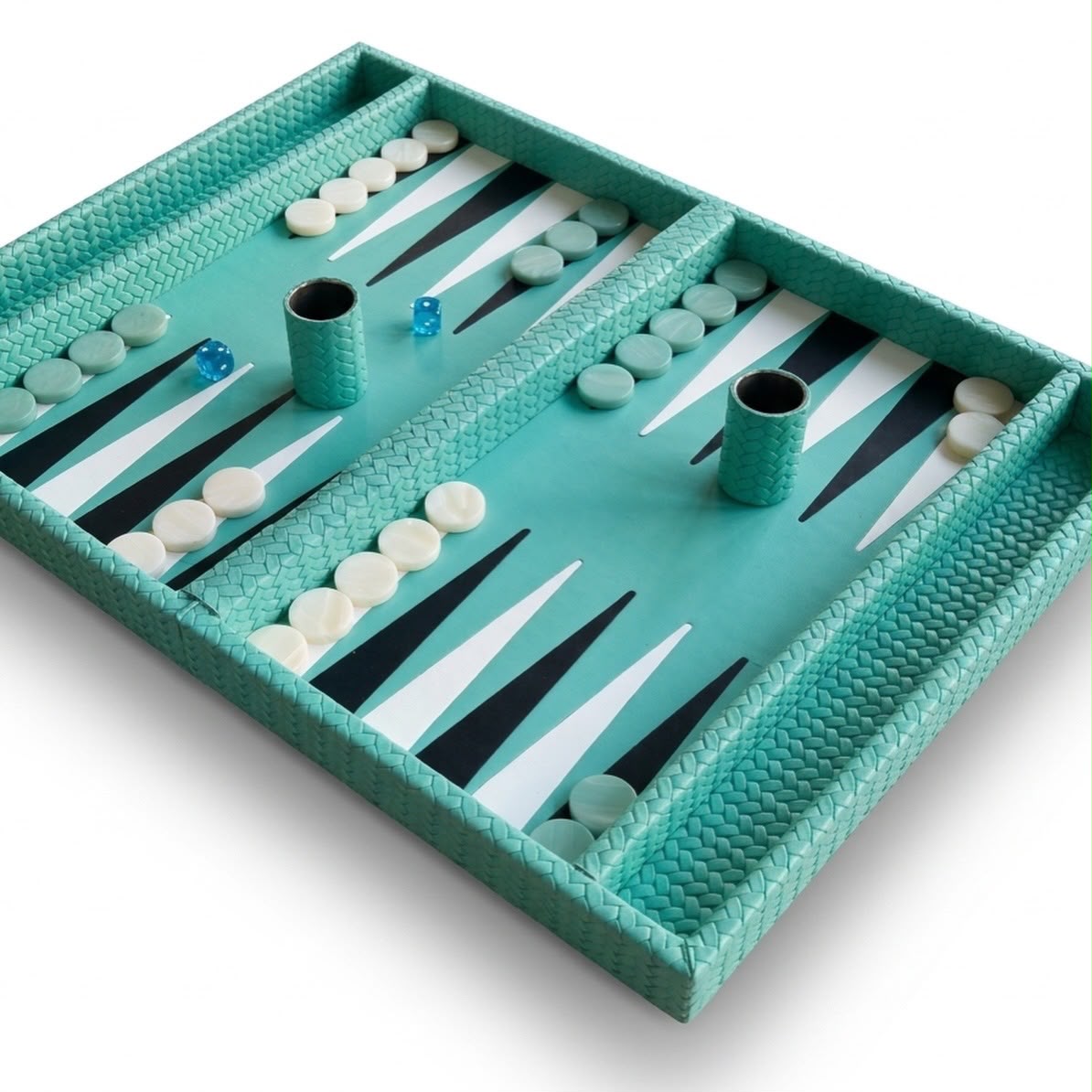 Close angle across the backgammon bed, black and white points set inside turquoise woven leather 3 cm walls