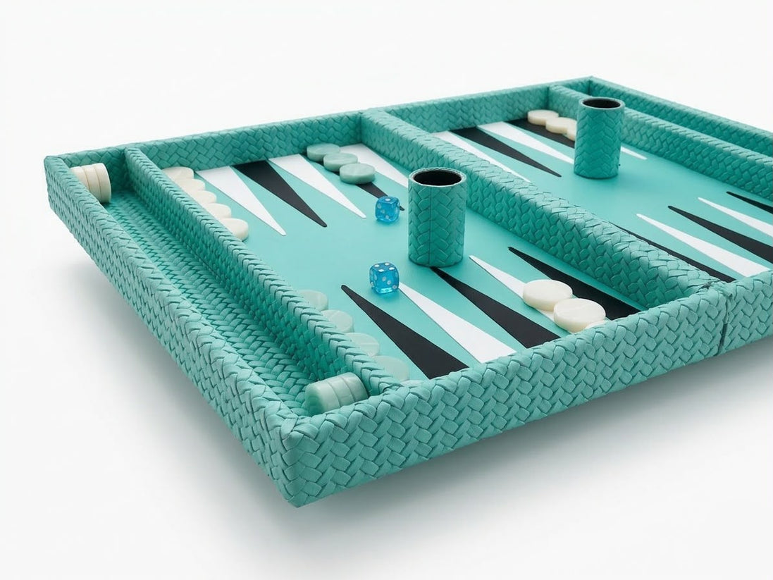 The 50 × 38 cm board angled, two leather-covered dice cups standing among the checkers on turquoise woven leather