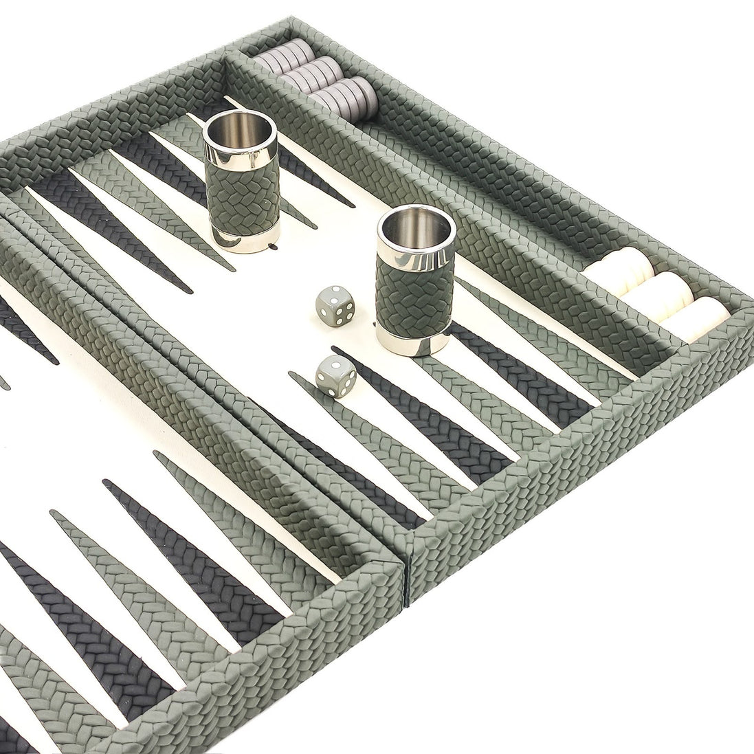 Sage green leather dice cups with polished rims on the ivory playing field of the backgammon board