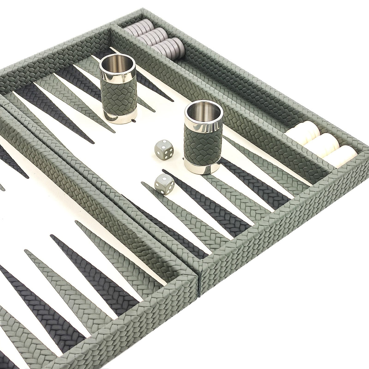 Sage green leather dice cups with polished rims on the ivory playing field of the backgammon board