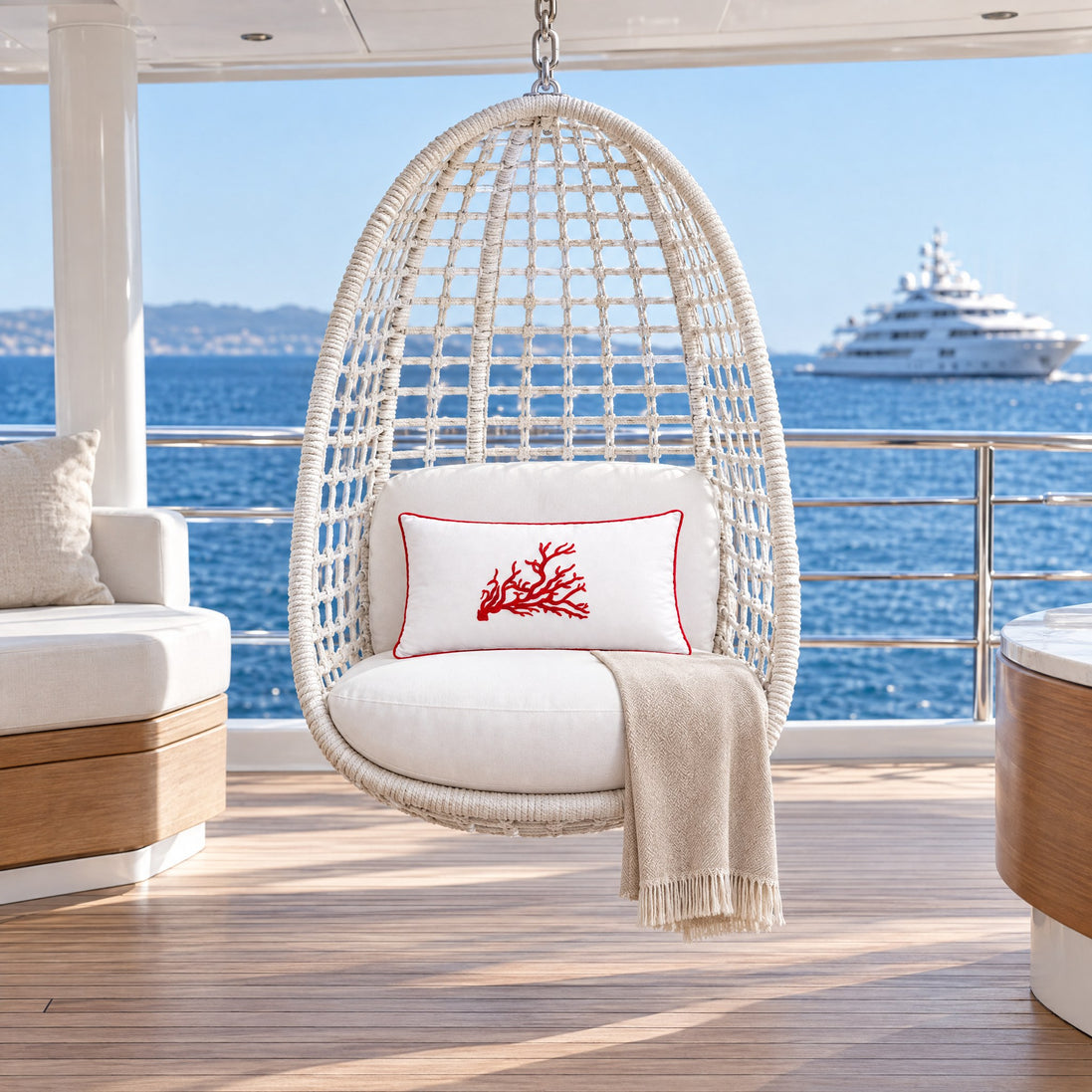 Coral Embroidered Rectangular Outdoor Cushion – White, red coral — a hanging egg chair of white woven rope on the upper deck