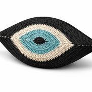 The black evil eye cushion at an angle, cream ring around the turquoise iris