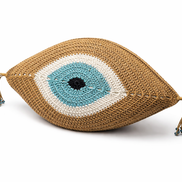 The camel evil eye cushion at an angle, crocheted rings around the iris