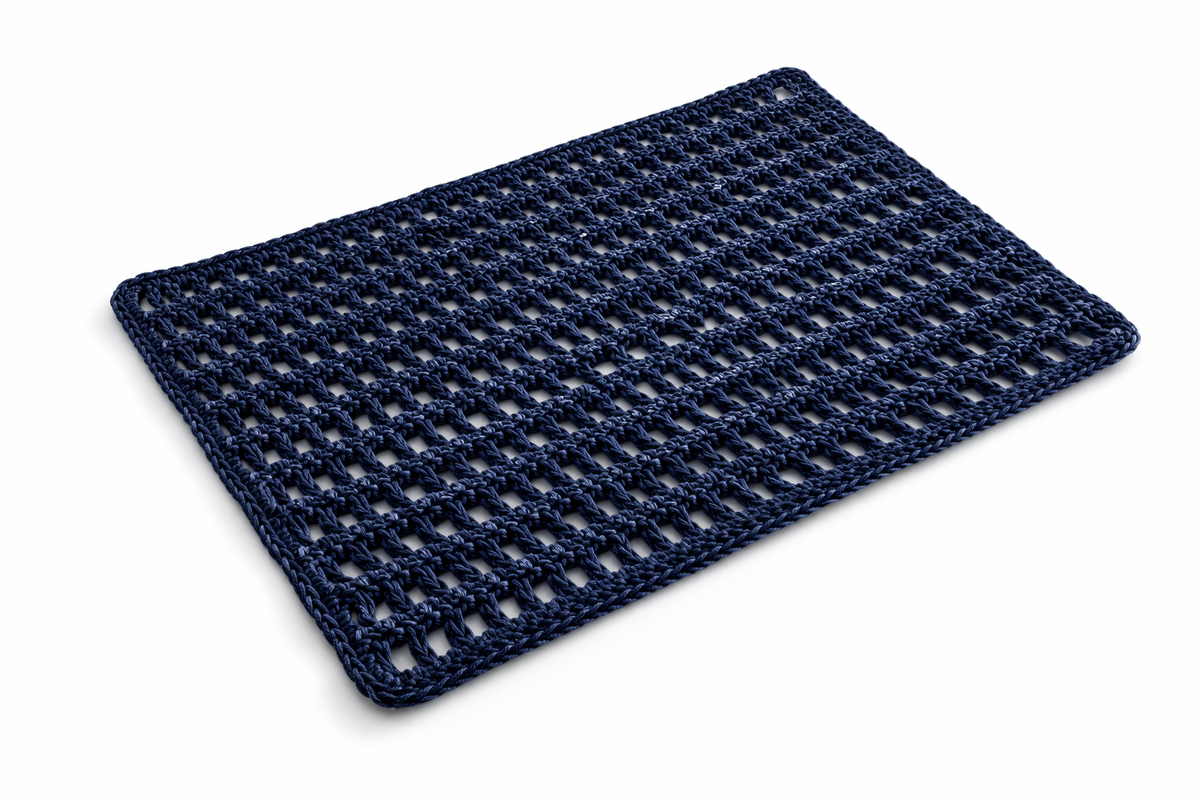 The navy leather cord placemat at an angle on a white ground